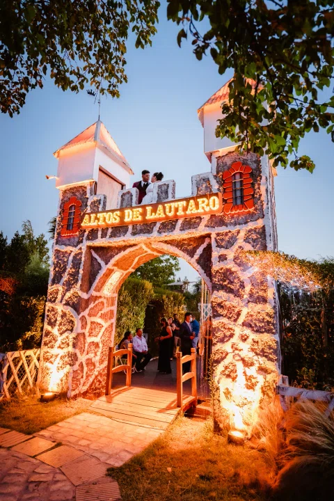 Arco de piedra de Altos de Lautaro iluminado de noche, con varias personas visibles en la entrada.