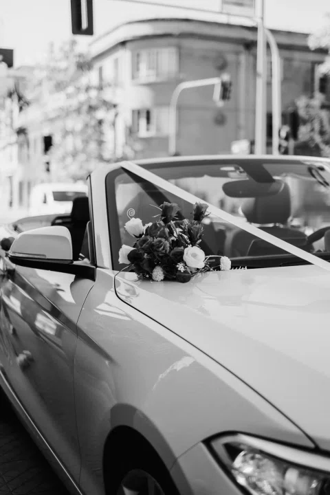 Automóvil descapotable decorado con un ramo y una cinta, fotografiado en blanco y negro.