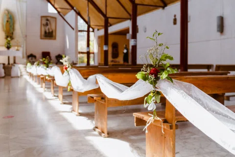 Bancas de la iglesia decoradas con telas blancas a lo largo del pasillo.