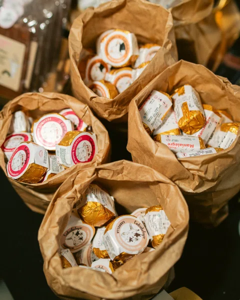Bolsas de papel llenas de productos envueltos en papel dorado y etiquetas circulares.