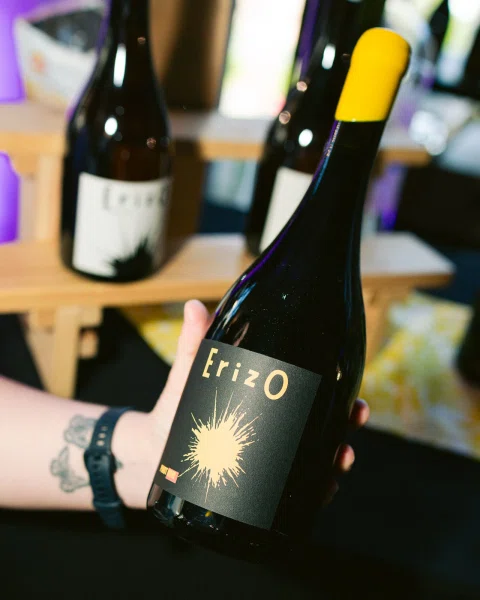 Mano sosteniendo una botella de vino con etiqueta negra y detalle dorado.