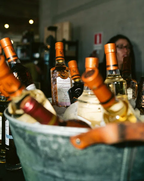 Varias botellas con tapas naranjas en una cubeta metálica con hielo.