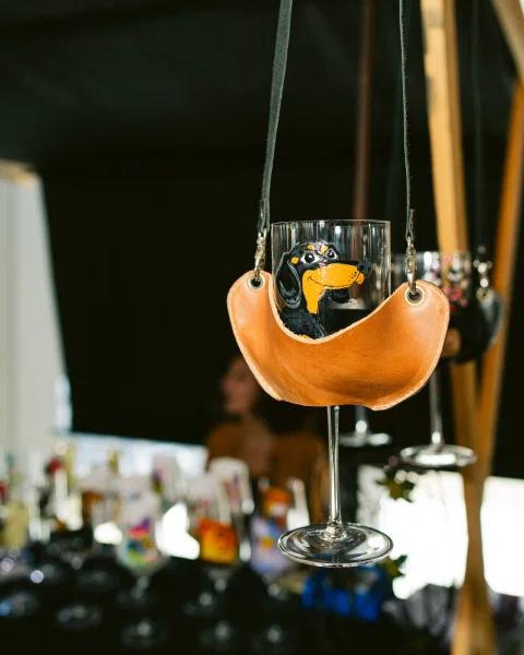 Copa con un dibujo de perro, suspendida en un soporte de cuero.