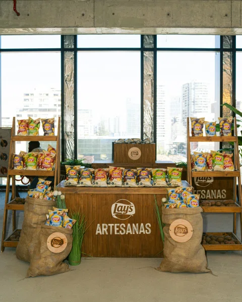 Exhibición de bolsas Lay's Artesanas sobre estanterías y una mesa de madera.