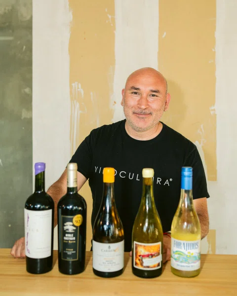 Hombre detrás de una mesa con cinco botellas de vino alineadas.