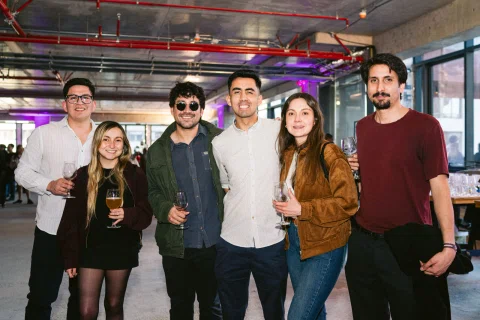 Grupo de seis personas posando con copas en un espacio interior.