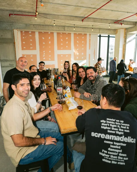 Grupo de personas sentado alrededor de una mesa larga con copas y aperitivos.