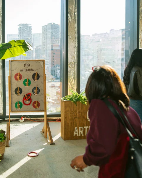 Persona apunta con un aro hacia un tablero de juego de Lay's Artesanas junto a una ventana.