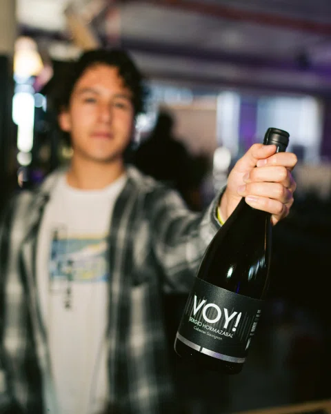 Persona sostiene una botella Voyi hacia la cámara con el fondo desenfocado.