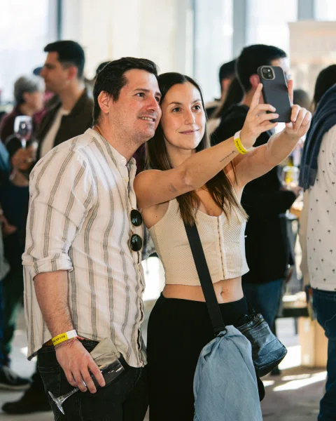 Dos personas posan para una selfie entre otros asistentes.