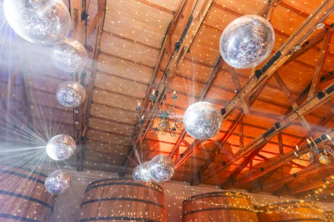 Bolas de espejos cuelgan del techo de madera iluminado sobre la pista de baile.