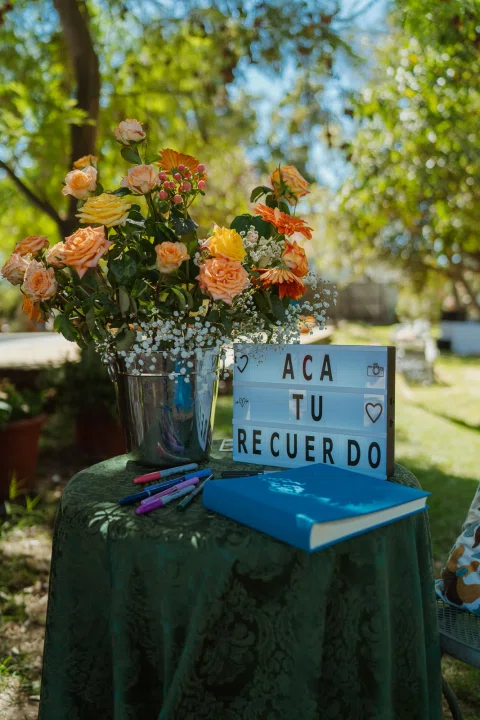 Cartel azul con un mensaje colocado junto a un arreglo de flores del jardín.