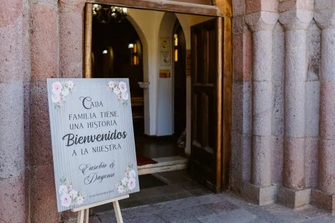 Cartel de bienvenida colocado junto a la entrada de piedra de la iglesia.