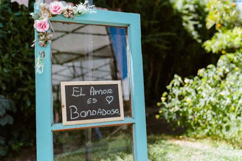 Cartel con la frase “El amor es bondadoso” sobre un marco azul decorado con flores.