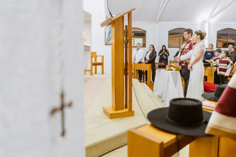 Cruz desenfocada en primer plano junto al púlpito y el altar de la iglesia.
