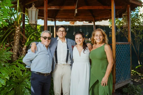 Cuatro adultos posan juntos frente a un gazebo de madera en el jardín.