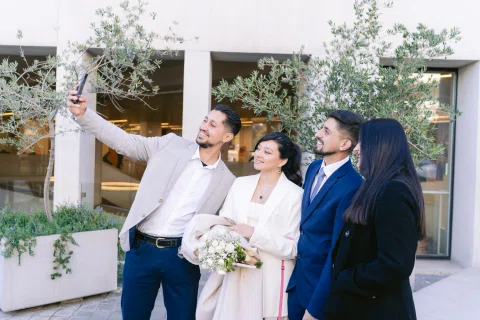 Cuatro personas posan para una selfie al aire libre; una de ellas sostiene un ramo.