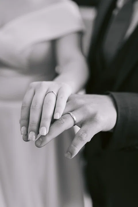 Detalle en blanco y negro de las manos de un hombre y una mujer apoyadas juntas.