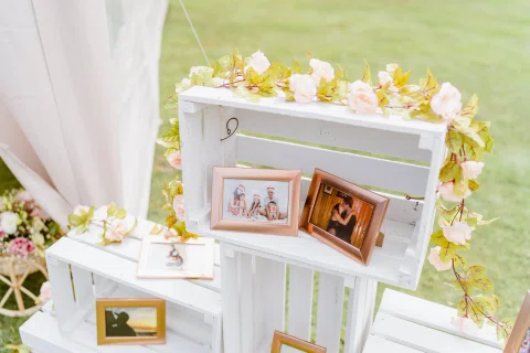 Detalle de un exhibidor de madera con fotografías enmarcadas, flores y pequeños adornos.