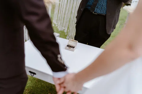 Detalle de las manos de un hombre y una mujer sobre una mesa blanca durante la ceremonia.