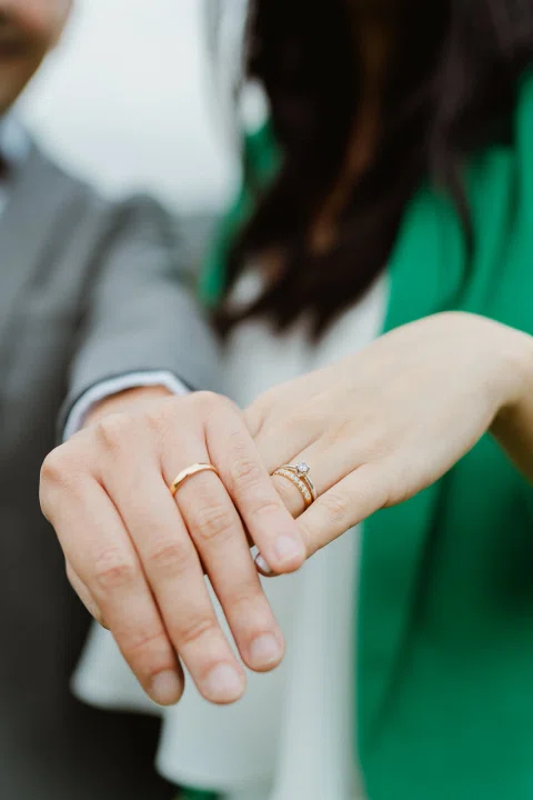 Detalle de las manos de una mujer con blazer verde mostrando un anillo.