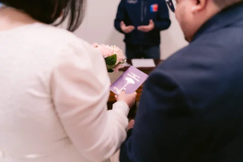 Detalle de manos sosteniendo un pequeño cuaderno morado.