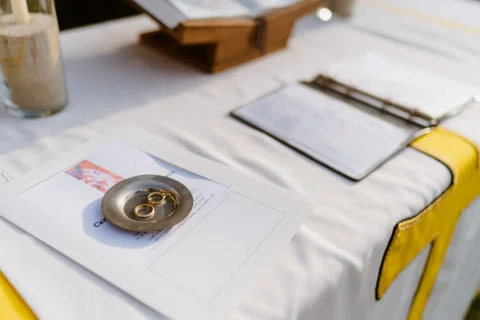 Dos anillos descansan sobre un pequeño platillo metálico junto a documentos sobre una mesa.