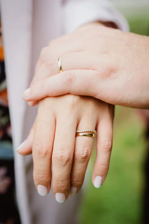 Dos manos superpuestas muestran anillos dorados en primer plano.