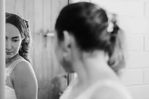 Mujer con vestido blanco mira a otra mujer desenfocada en primer plano, en una fotografía en blanco y negro.