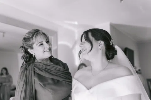 Dos mujeres se miran y sonríen en una fotografía en blanco y negro.