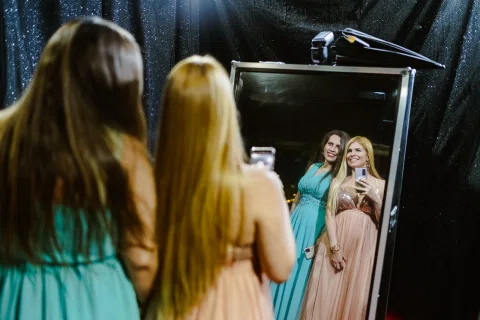 Dos mujeres se fotografían con un teléfono frente a un espejo.