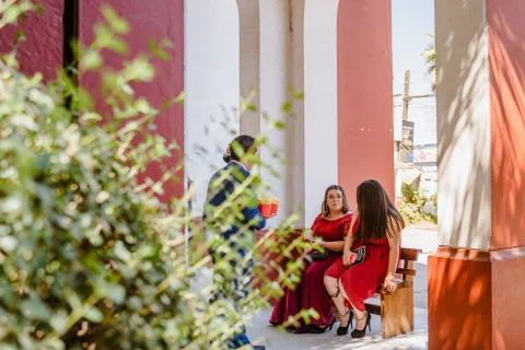 Dos mujeres sentadas junto a un muro con plantas en el exterior de la iglesia.