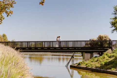 Dos personas vistas a distancia sobre un puente que cruza un canal de agua.