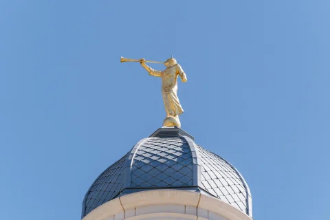 Estatua dorada sobre una cúpula azul contra un cielo despejado.