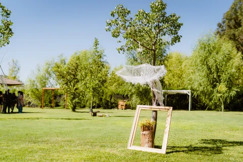 Estructura decorativa con tela blanca y un espejo apoyado sobre el césped en el jardín.