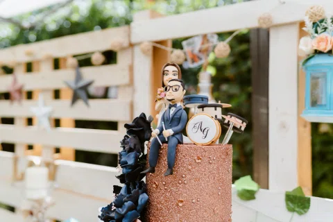 Dos figuras decorativas junto a una batería aparecen en la parte superior de una torta.