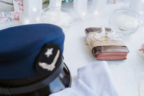 Gorra de uniforme en primer plano junto a pequeños accesorios sobre una mesa.