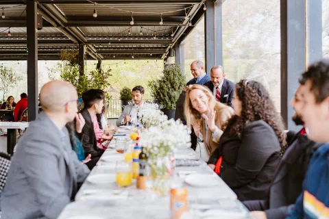 Grupo de personas compartiendo alrededor de una mesa en una terraza.