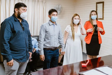 Grupo de personas con mascarillas reunidas dentro de la sala del registro civil.
