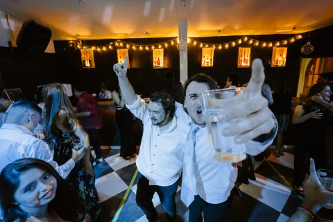 Grupo de hombres bailando con los brazos levantados durante la fiesta.