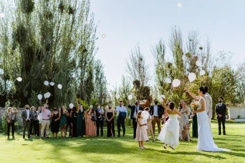 Grupo de personas soltando globos blancos en el jardín.