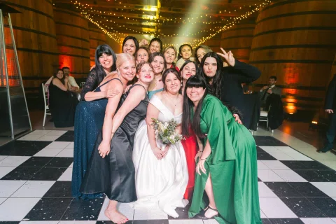 Grupo de mujeres posa junto a una mujer con vestido blanco en el centro de la pista.