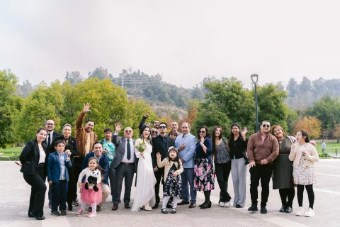 Grupo numeroso posa al aire libre mientras varias personas levantan los brazos.