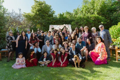 Grupo numeroso de personas posa junto en el jardín, con algunas sentadas y otras de pie.
