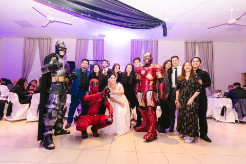 Grupo numeroso posa dentro del salón junto a varias personas con disfraces de colores.