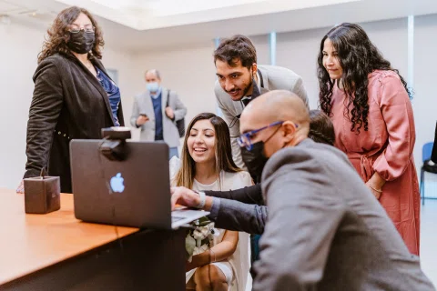Grupo reunido alrededor de un computador portátil sobre una mesa.