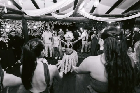 Grupo de personas baila formando un círculo, en una fotografía en blanco y negro.