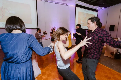 Grupo de personas baila junto sobre la pista de un salón.