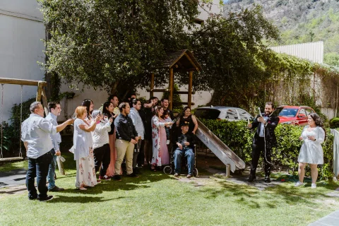 Grupo de personas levanta copas durante un brindis en un jardín.