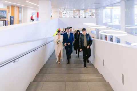 Grupo de personas camina por un pasillo largo y luminoso dentro de un edificio.